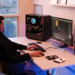 a person sitting at a desk with a computer and speakers